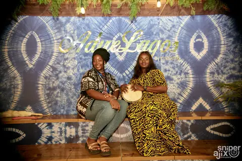 Two women pose in front of an indigo tie-dye backdrop.