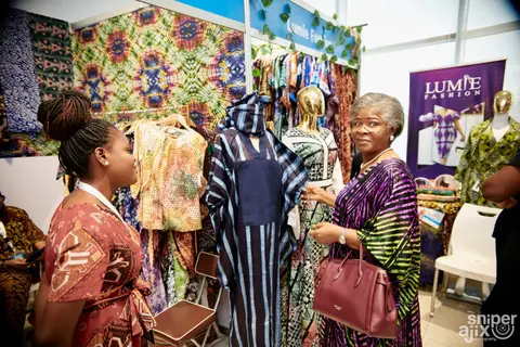 Shoppers browse adire garments at an exhibitor stall.