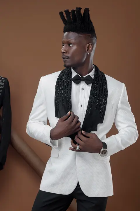 A model in a white brocade jacket looks away over his shoulder.