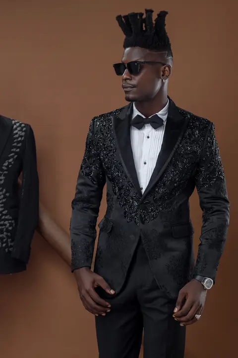 A model in a black embellished tuxedo jacket and sunglasses.