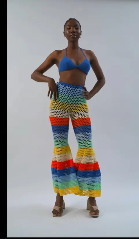 A model in a rainbow crochet set against a white cyc, from Amarelis Dark.