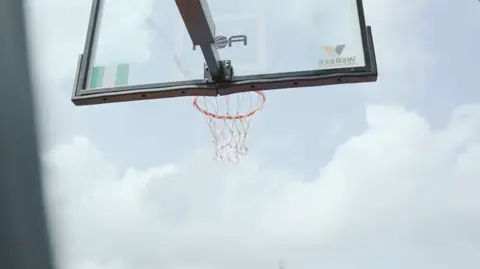 Looking up at a basketball hoop against the sky, from AOA DocuFilm.