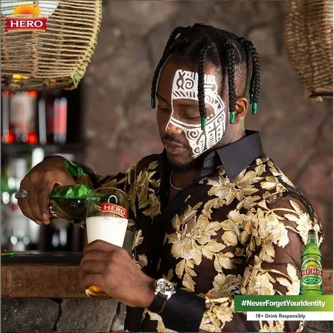 A man with painted face pours Hero Lager at a bar.