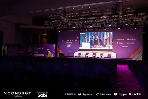 Wide view of the Moonshot main stage glowing purple and blue before the audience.