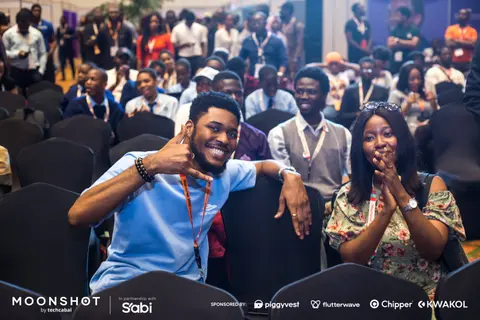 Attendees laugh and gesture from their seats during a session.