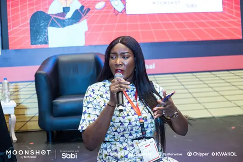 A woman speaks into a microphone in front of the Creative Economy stage.