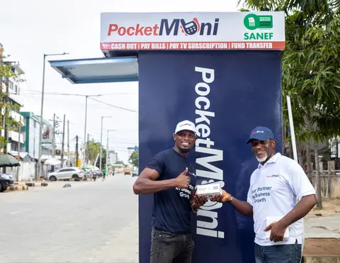 Two men in PocketMoni shirts outside a branded street kiosk.