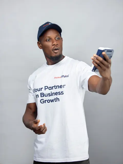 A man in a PocketMoni tee looks at a terminal in surprise.