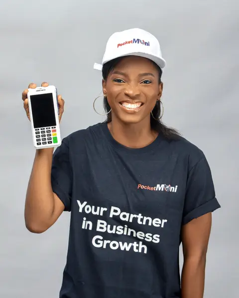 A woman in a PocketMoni cap holds a terminal up to camera, smiling.