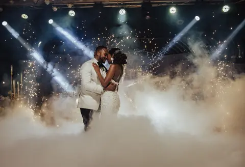 The couple kiss through fog and falling sparks on the dance floor.