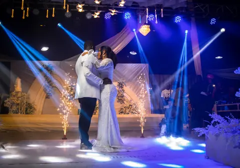 The couple share their first dance under blue and white beams of stage light.